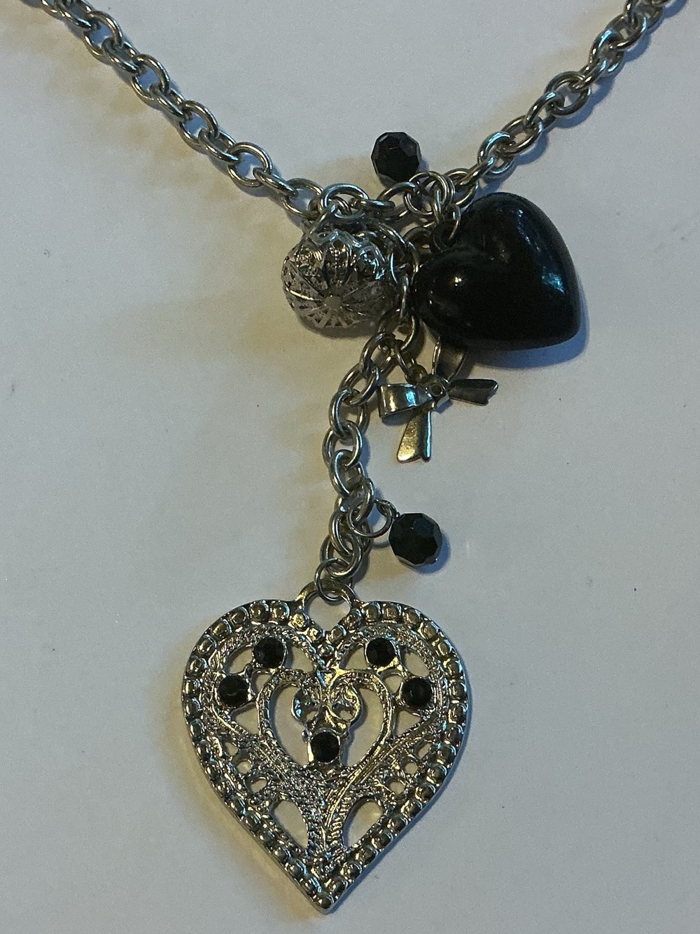 Necklace with a Large Filigree Heart Pendant and Smaller Black and Silver Charms